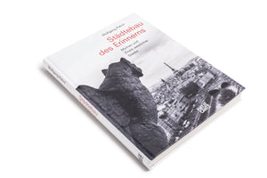 Eine Schrägansicht des Buches Städtebau des Erinnerns von Wolfgang Pehnt auf einem weißen Hintergrund. Das Cover zeigt eine Schwarz-Weiß-Fotografie von Paris mit dem Eiffelturm, gesehen von hinter einer steinernen Figur. Der Titel ist in Rot gedruckt, der Name des Autors und der Untertitel in Schwarz.