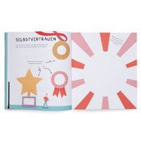 Ein aufgeschlagenes Kinderbuch zum Thema Selbstvertrauen. Auf der linken Seite sind eine Medaille, ein Pokal und eine Schleife abgebildet, mit der Aufforderung, drei Dinge aufzuschreiben, die man gut kann. Die rechte Seite hat einen leeren Kreis mit roten Strahlen, in den ein Bild gezeichnet werden soll.