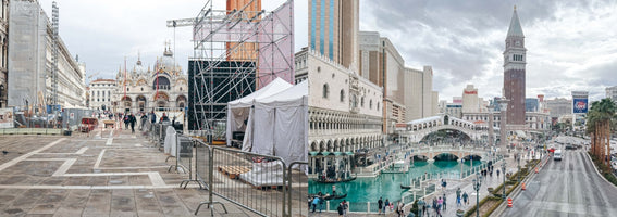 Ein geteiltes Panoramabild, das den echten Markusplatz in Venedig mit einer Baustelle links mit der idealisierten Nachbildung von Venedig im Venetian Hotel in Las Vegas rechts vergleicht, komplett mit Kanälen, Gondeln und nachgebauten Wahrzeichen.