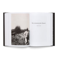Aufgeschlagenes Buch mit einer Schwarz-Weiß-Fotografie eines Mannes mit Hut in einer Wiese auf der linken Seite und der Kapitelüberschrift Der monumentale Munch (1909–1914) auf der rechten Seite.
