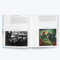 Ein aufgeschlagenes Buch liegt auf einer weißen Oberfläche und zeigt die Seiten 42 und 43. Auf der linken Seite befindet sich deutscher Text und ein Schwarz-Weiß-Foto einer Kunstausstellung. Auf der rechten Seite ist weiterer Text und eine farbige Abbildung des Gemäldes Das kranke Kind von Edvard Munch zu sehen.