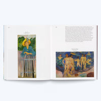 Ein aufgeschlagenes Kunstbuch auf einer weißen Oberfläche. Auf der linken Seite ist ein Gemälde einer Frau mit gelbem Hut, die an einem Zaun lehnt. Auf der rechten Seite befindet sich ein Textabschnitt und darunter ein Gemälde von nackten Männern an einem Ufer.